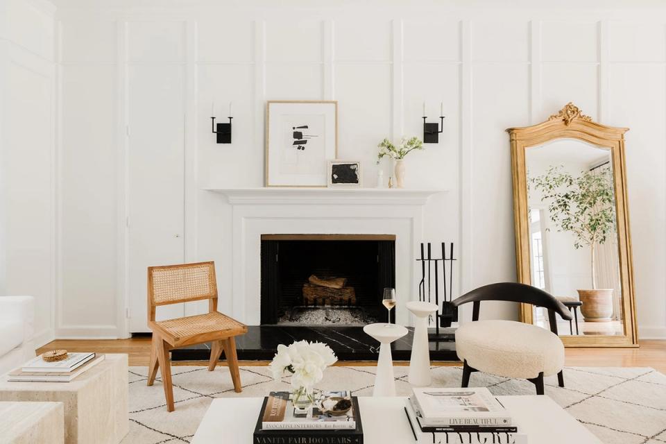 Scandinavian fireplace vignette with white walls, natural wood furniture, black accents, and minimalist gallery display