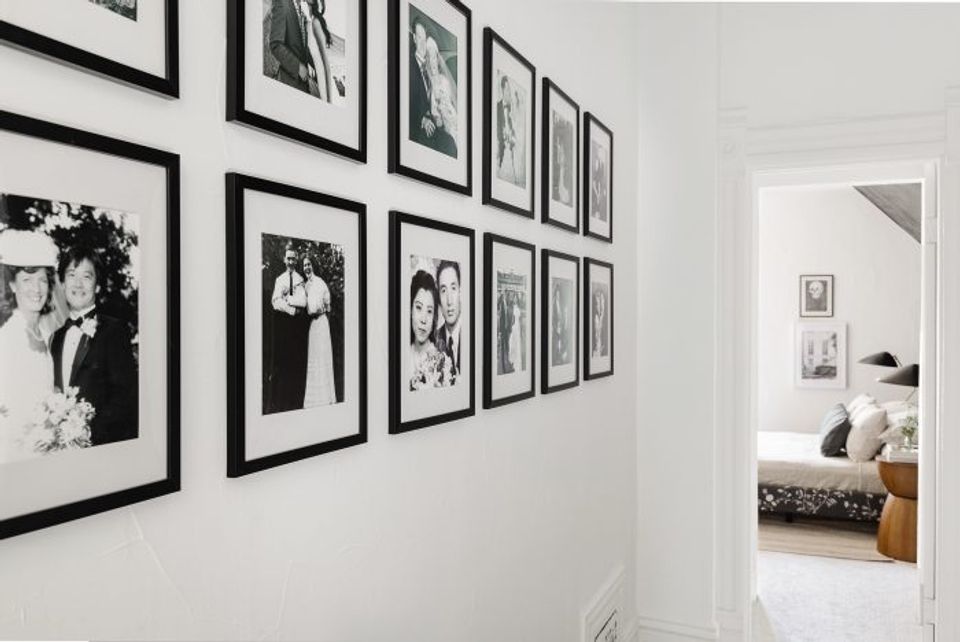 Modern black-and-white gallery wall with framed photographs creating bold geometric grid pattern in bright hallway entry.