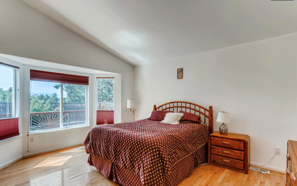 Warm traditional bedroom with burgundy accents, hardwood floors, and natural light from corner windows