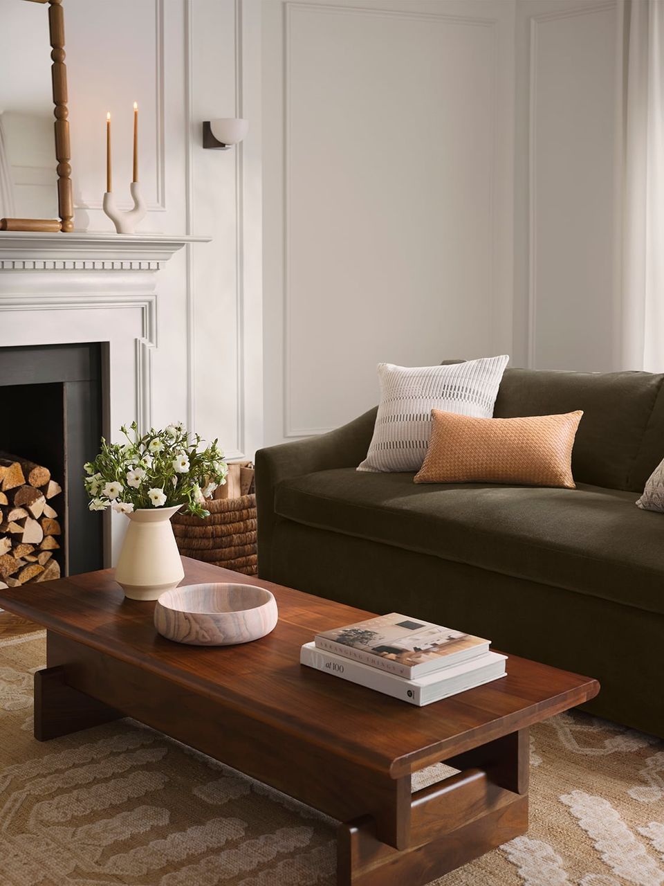 Minimalist living room blending dark green sofa with warm wood coffee table, fireplace, and neutral beige walls for sophisticated elegance