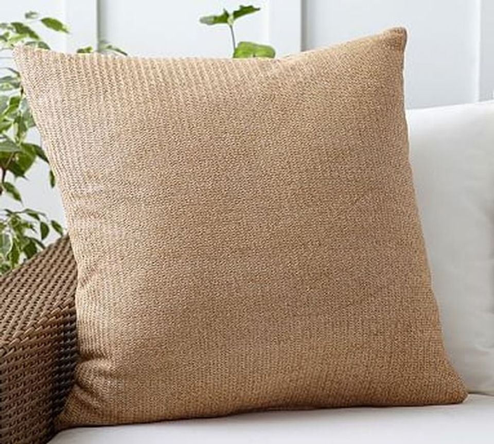 Neutral textured throw pillow in warm beige with natural fiber weave, creating a coastal-casual patio aesthetic