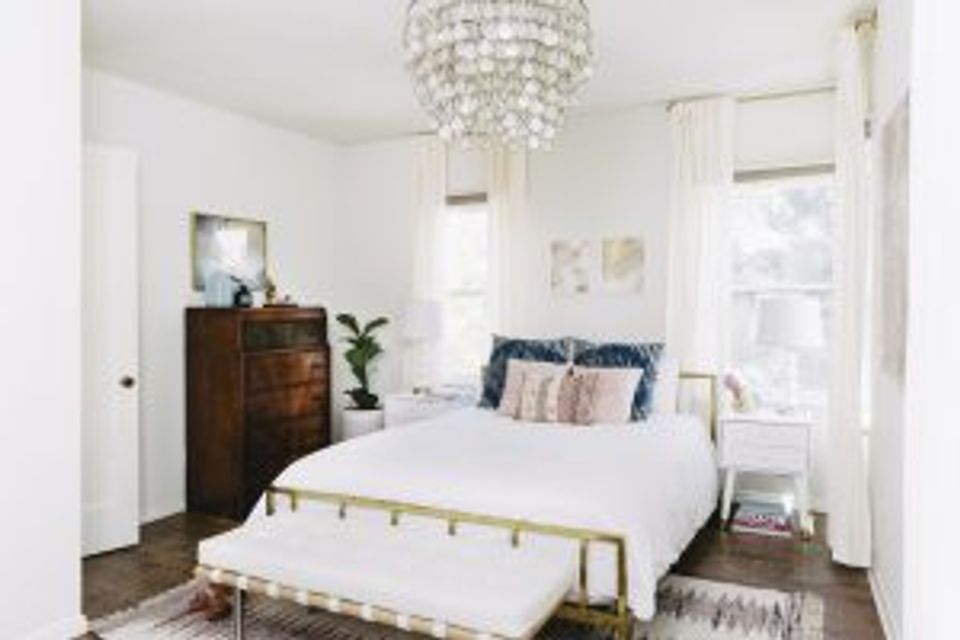 Serene primary bedroom with crystal chandelier, dark wood furniture, and minimalist aesthetic