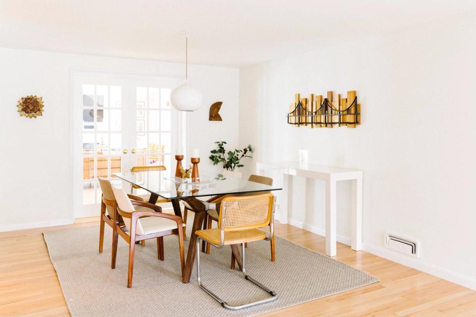 Bright mid-century modern dining room with warm wood tones, glass table, tapered legs, and autumn gold accents