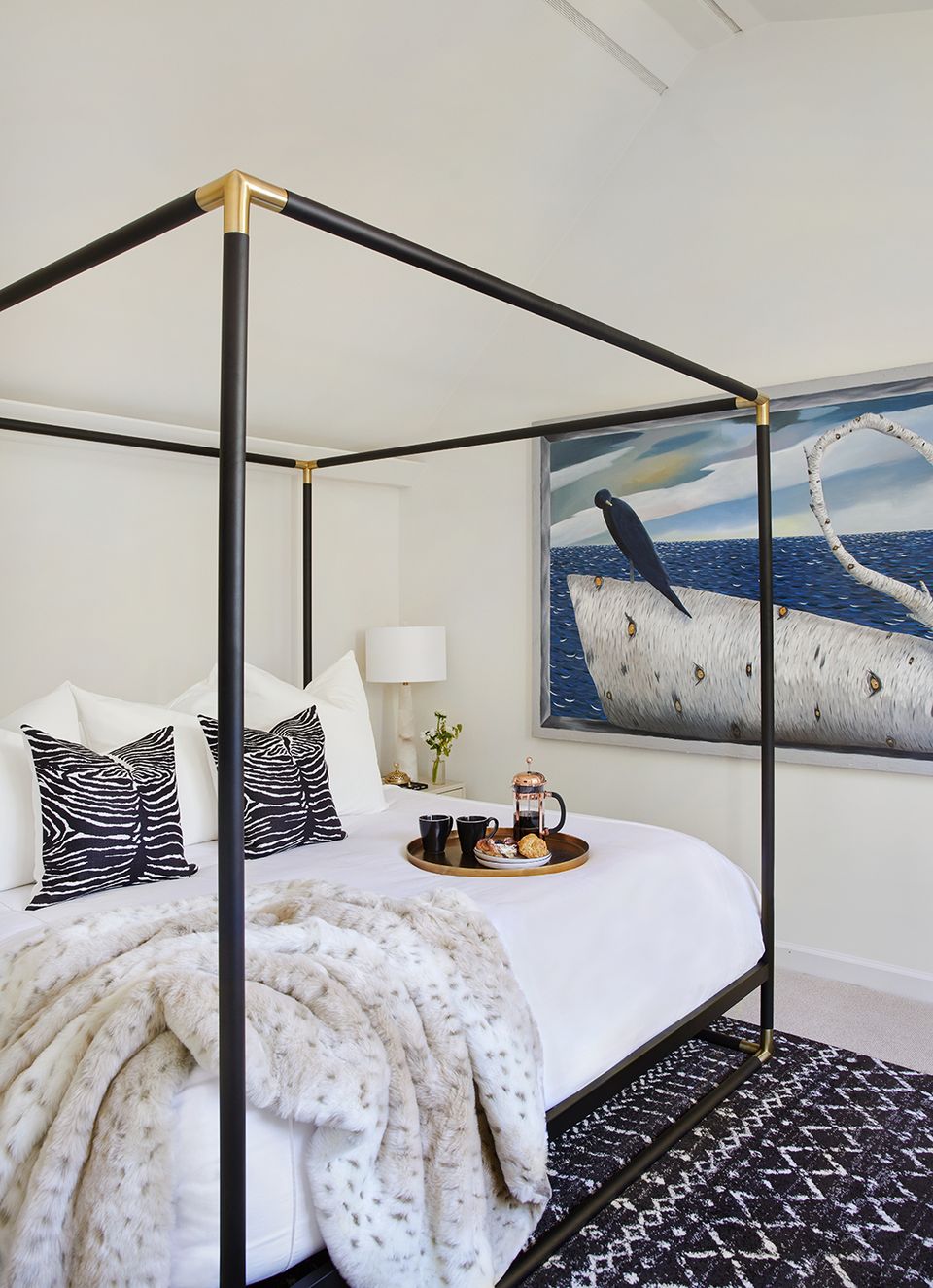 Contemporary canopy bed with black frame, nautical artwork, graphic patterned textiles