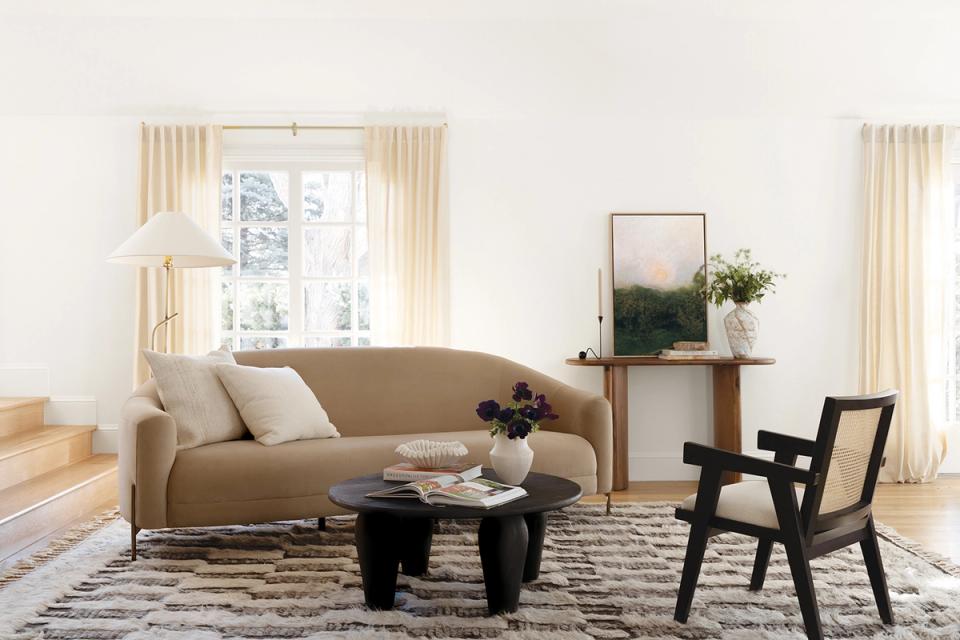 Minimalist living room with warm neutral palette, camel sofa, and mid-century modern black chair