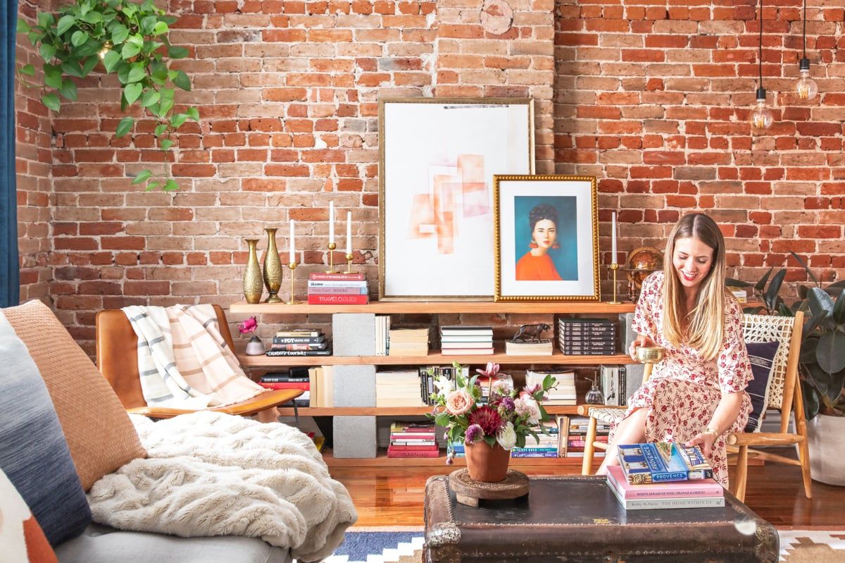 Eclectic bohemian living room with exposed brick walls, vintage furniture, and gallery wall art in warm earth tones