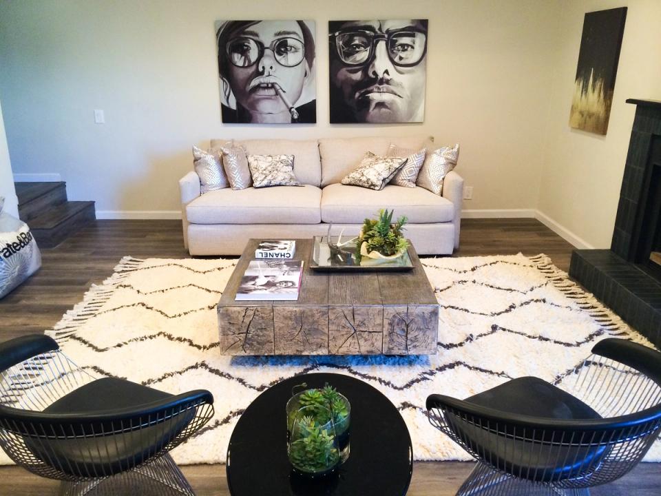 Contemporary living room blending cream upholstery with bold black art and woven accent chairs