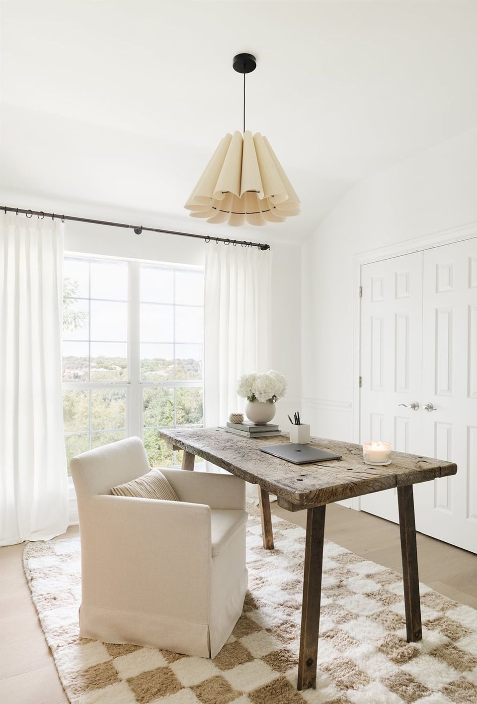 Bright coastal home office with cream linen chair, reclaimed wood desk, woven pendant light, and geometric area rug