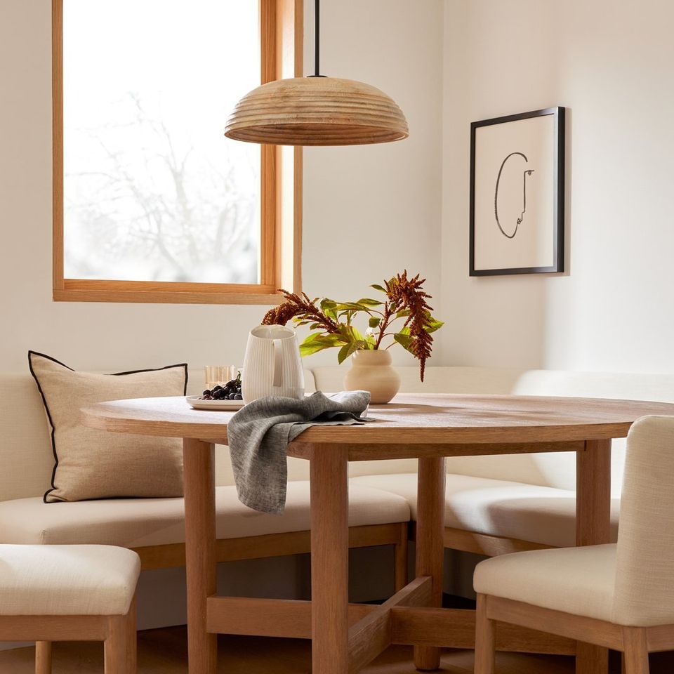 Warm mid-century dining space with wood table, natural pendant light, and neutral upholstered seating