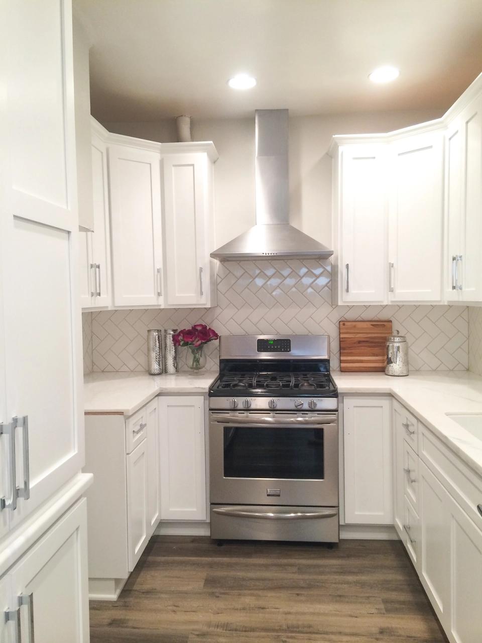 Contemporary white kitchen with stainless steel range, subway tile backsplash, and clean lines