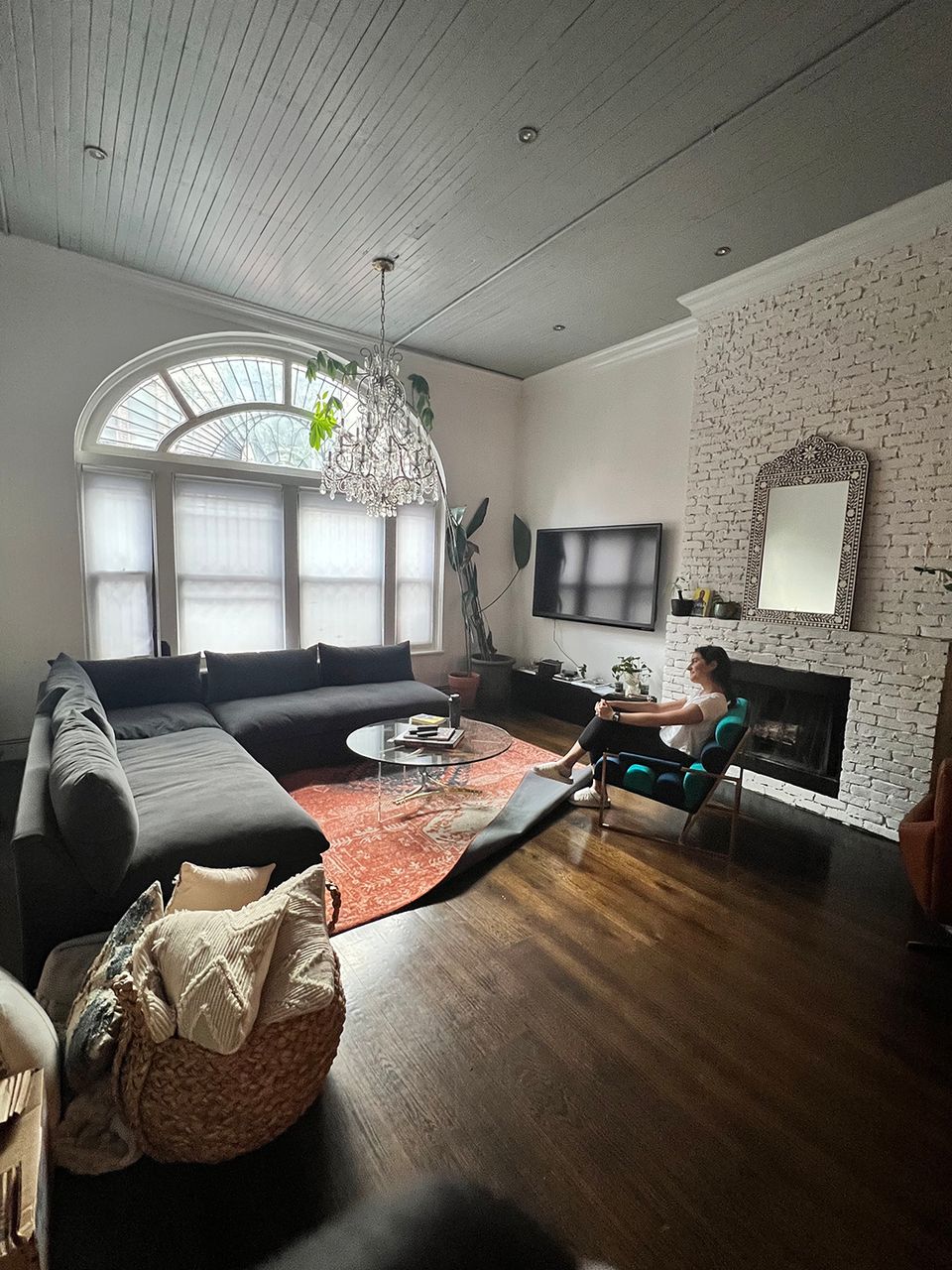 Transitional living room blending white shiplap ceiling, exposed brick, black sofa, and coral geometric rug
