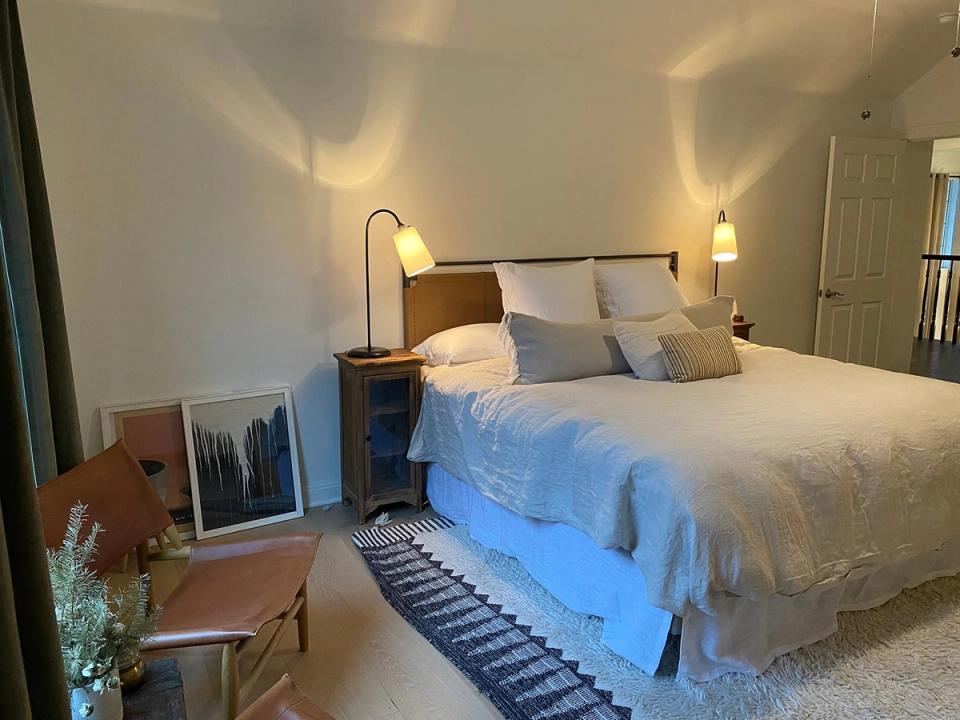 Warm mid-century modern bedroom featuring warm wood tones, soft ambient lighting, and layered neutral bedding.