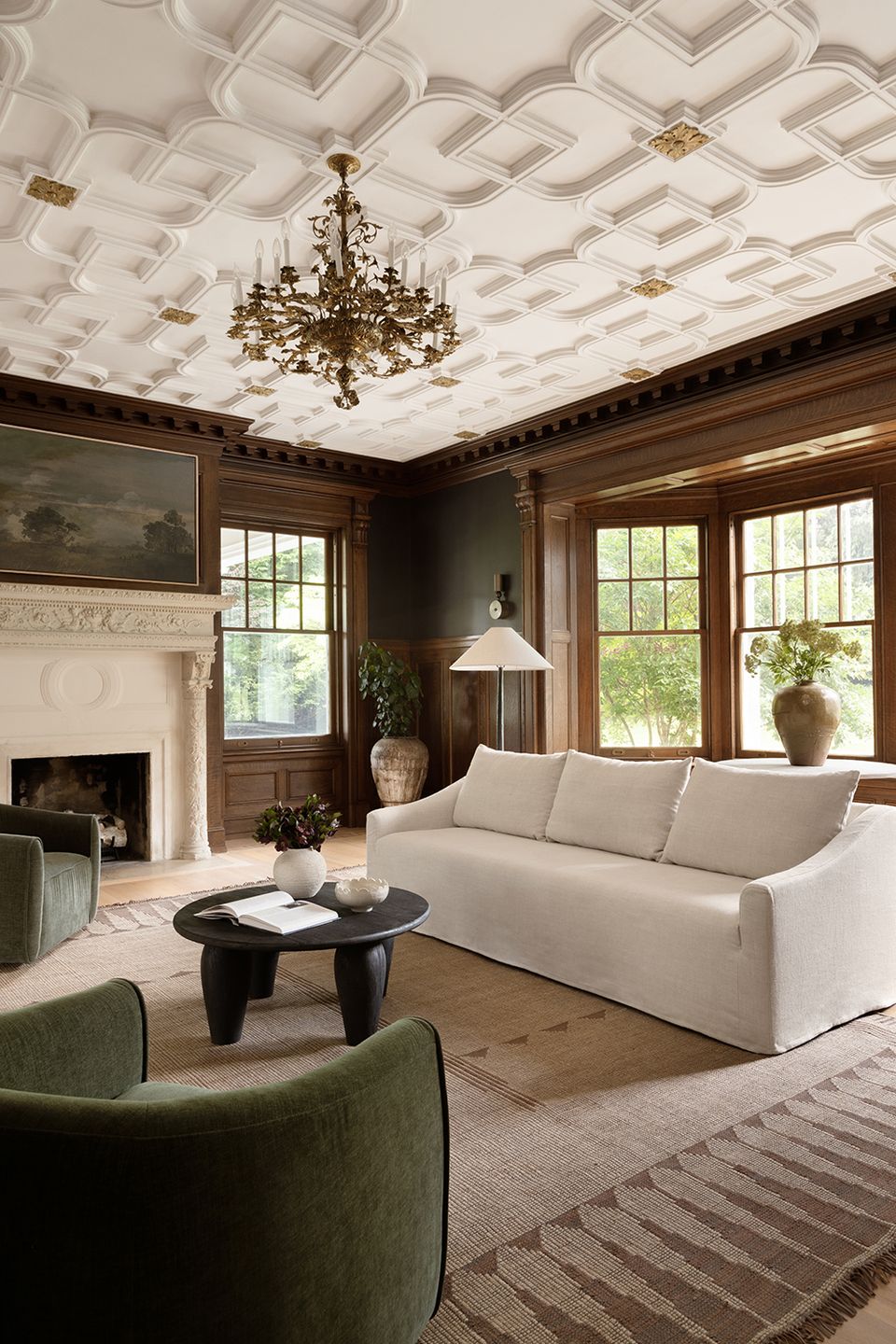 Elegant traditional space with coffered ceiling, cream sofa, dark wood, and brass chandelier