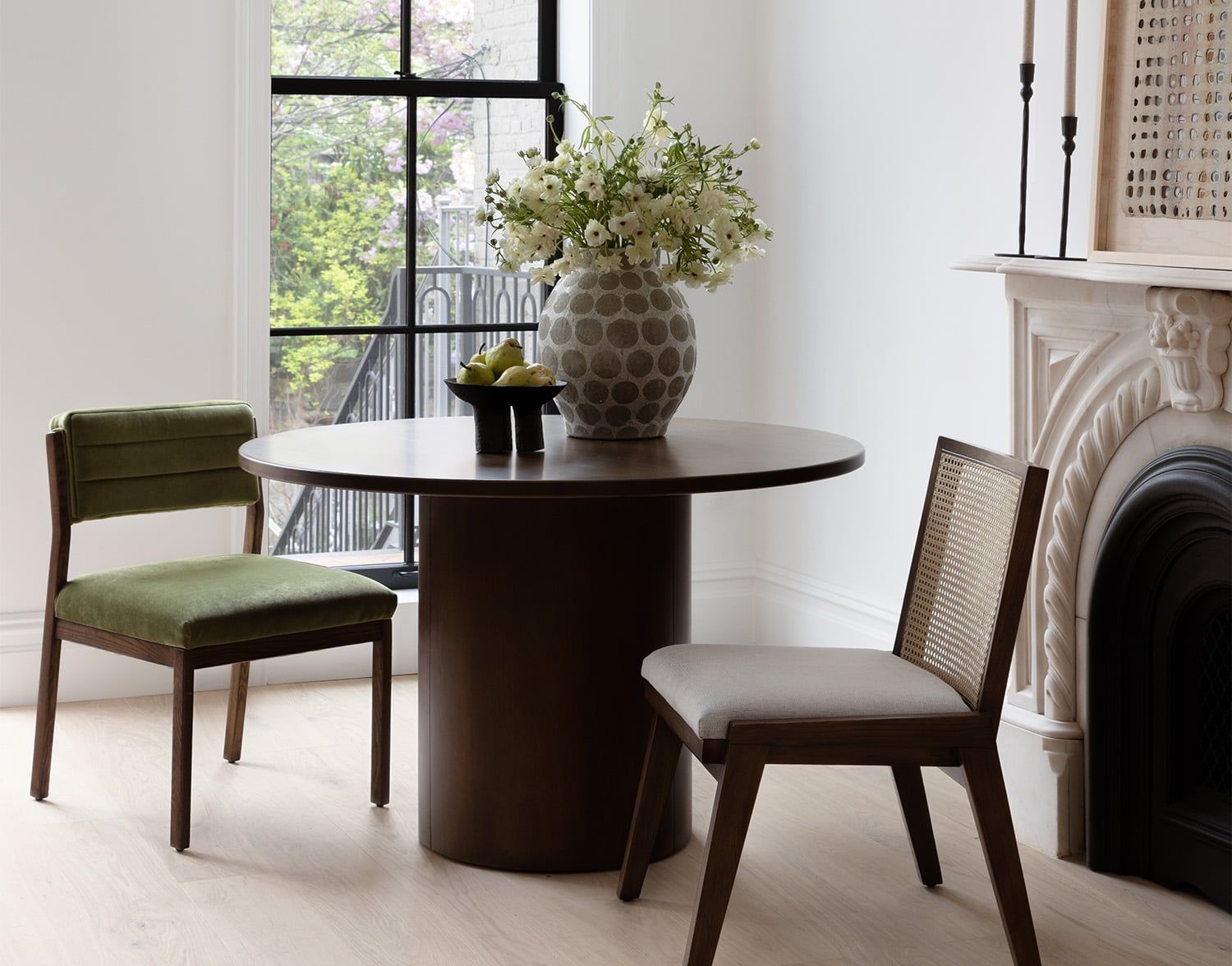 Minimalist dining space featuring contrasting dark and light wood tones with contemporary furniture and botanical accents