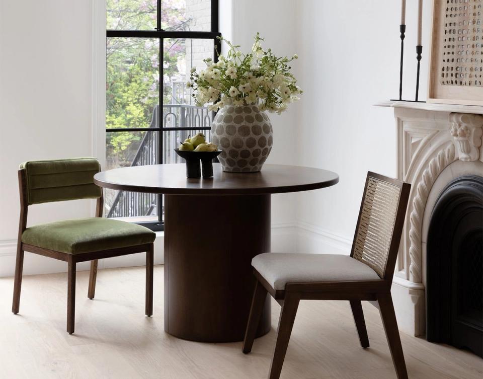 Minimalist dining space featuring contrasting dark and light wood tones with contemporary furniture and botanical accents