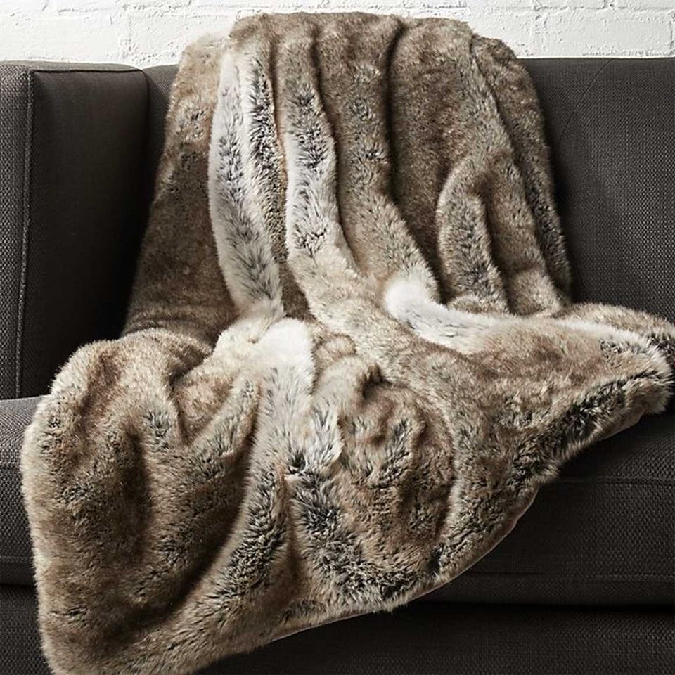 Cozy fall aesthetic with layered taupe and cream textured blankets on charcoal sofa