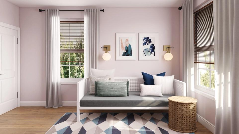 Scandinavian bedroom with blush walls, geometric patterned rug, and upcycled textile accents in navy and white