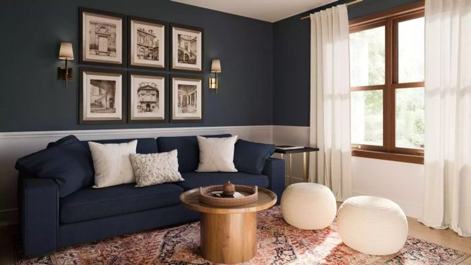 Moody navy living room with gallery wall and brass sconces providing warm accent lighting