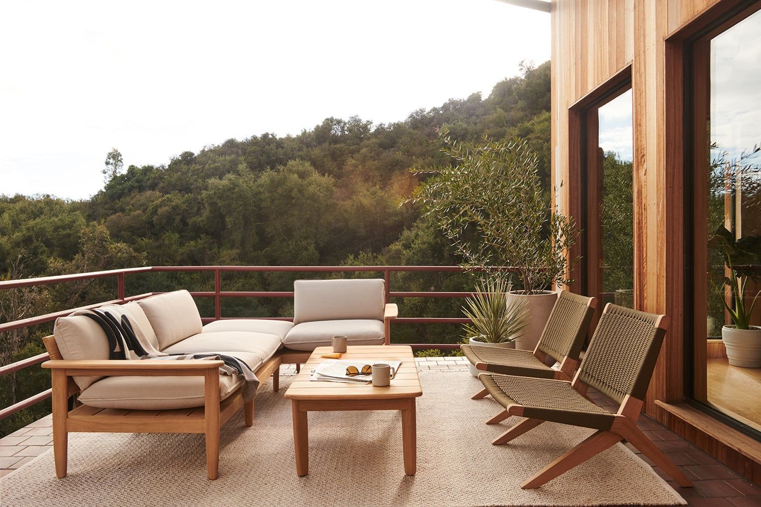 Mid-century modern patio with warm wood furniture, neutral cushions, and mountain views