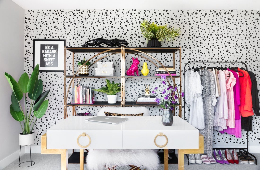 Modern minimalist home office with black pegboard wall, white marble desk, bright pink and magenta accents, potted plants, and organized storage shelving.