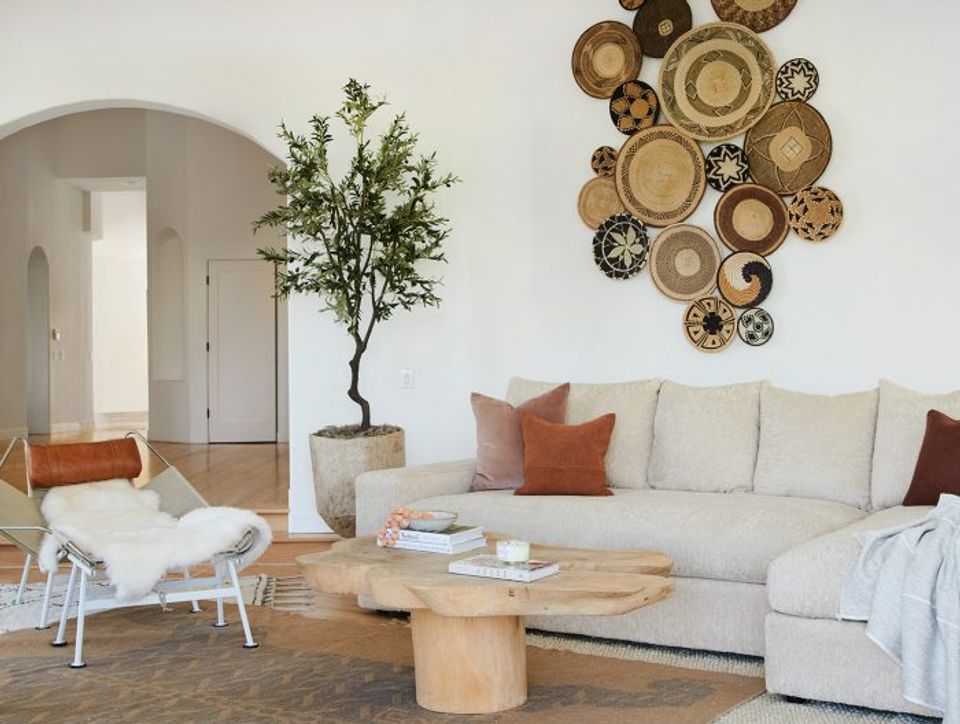 Scandinavian living room with woven basket wall display, cream sectional, natural wood accents, and minimalist decor.