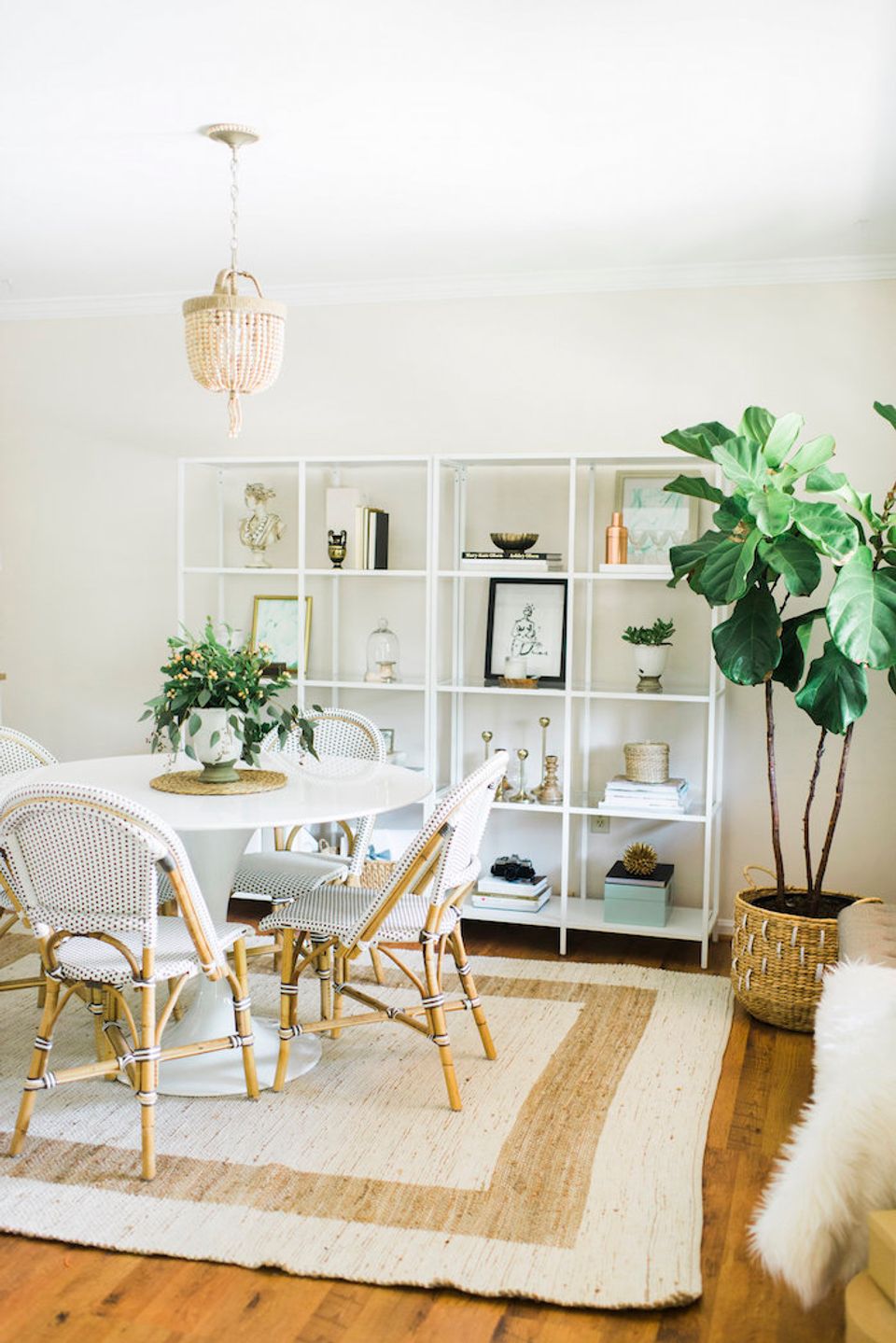 Bright bohemian workspace with rattan chairs, white shelving, and lush green plants