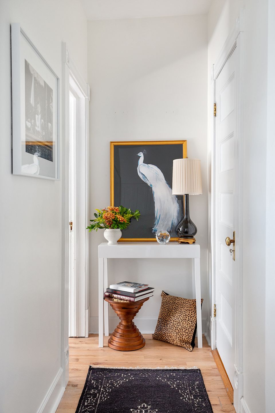 Bright entryway with eclectic gallery wall, white console table, warm wood accents, and botanical touches creating sophisticated transitional style