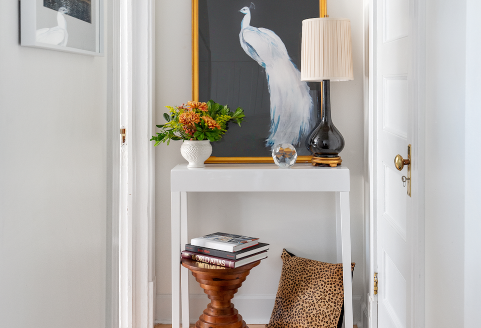 Minimalist alcove with charcoal accent wall, white shelving, peacock artwork, and warm wood accents creating a refined, curated aesthetic.
