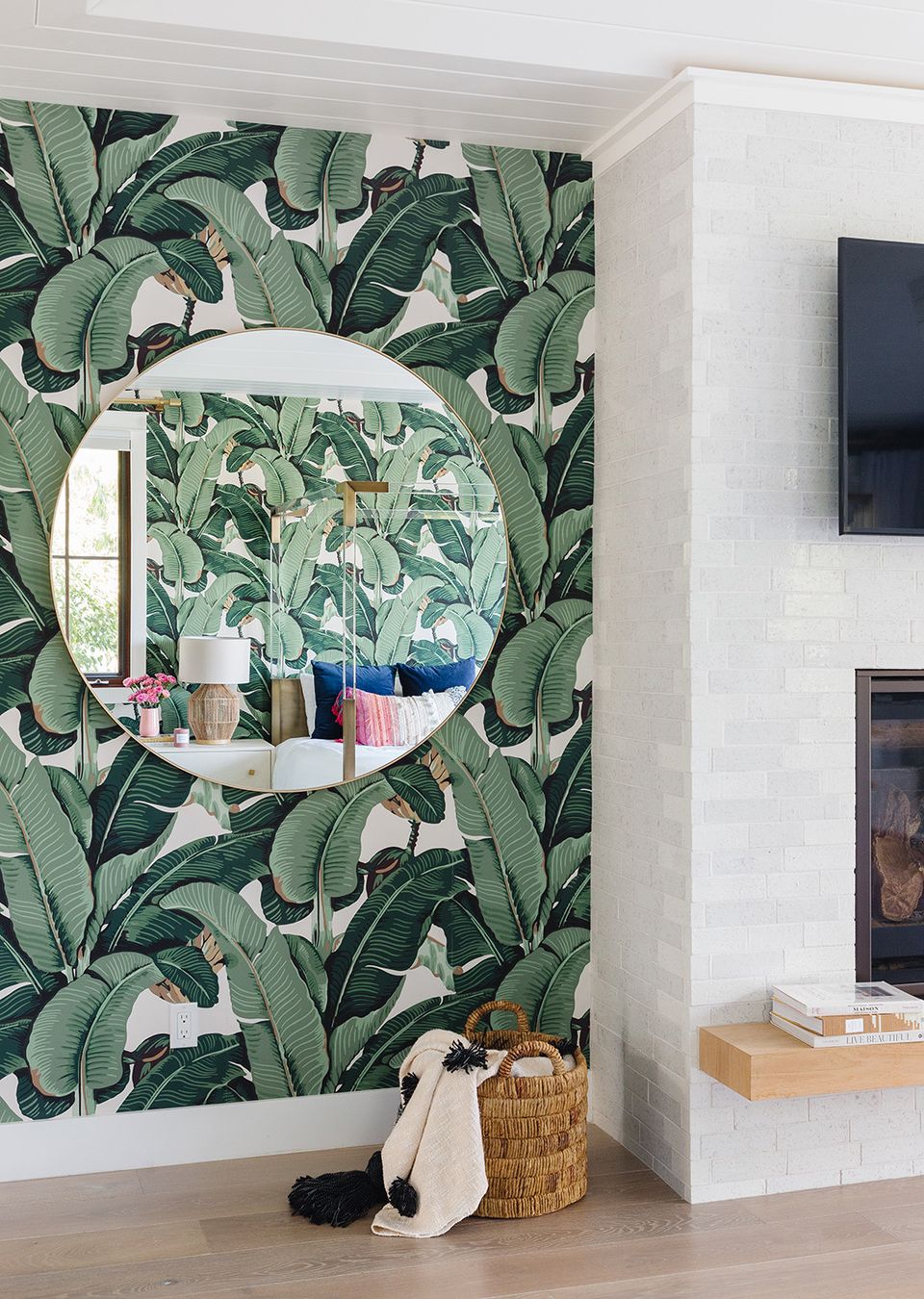 Tropical accent wall with bold green banana leaf wallpaper and modern circular mirror installation