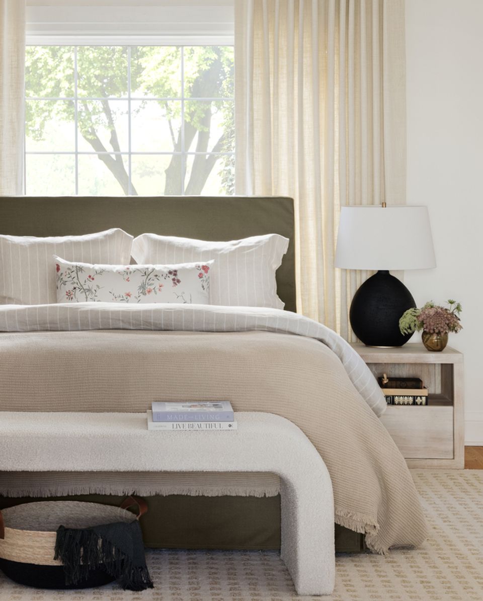 Calm bedroom with sage headboard, cream bedding, and soft neutral palette.
