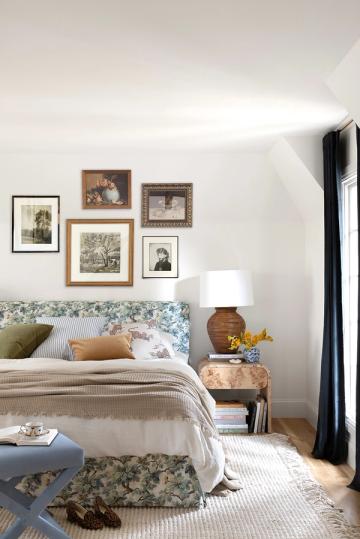 Bohemian bedroom with blue floral headboard, gallery wall, and natural wood nightstand