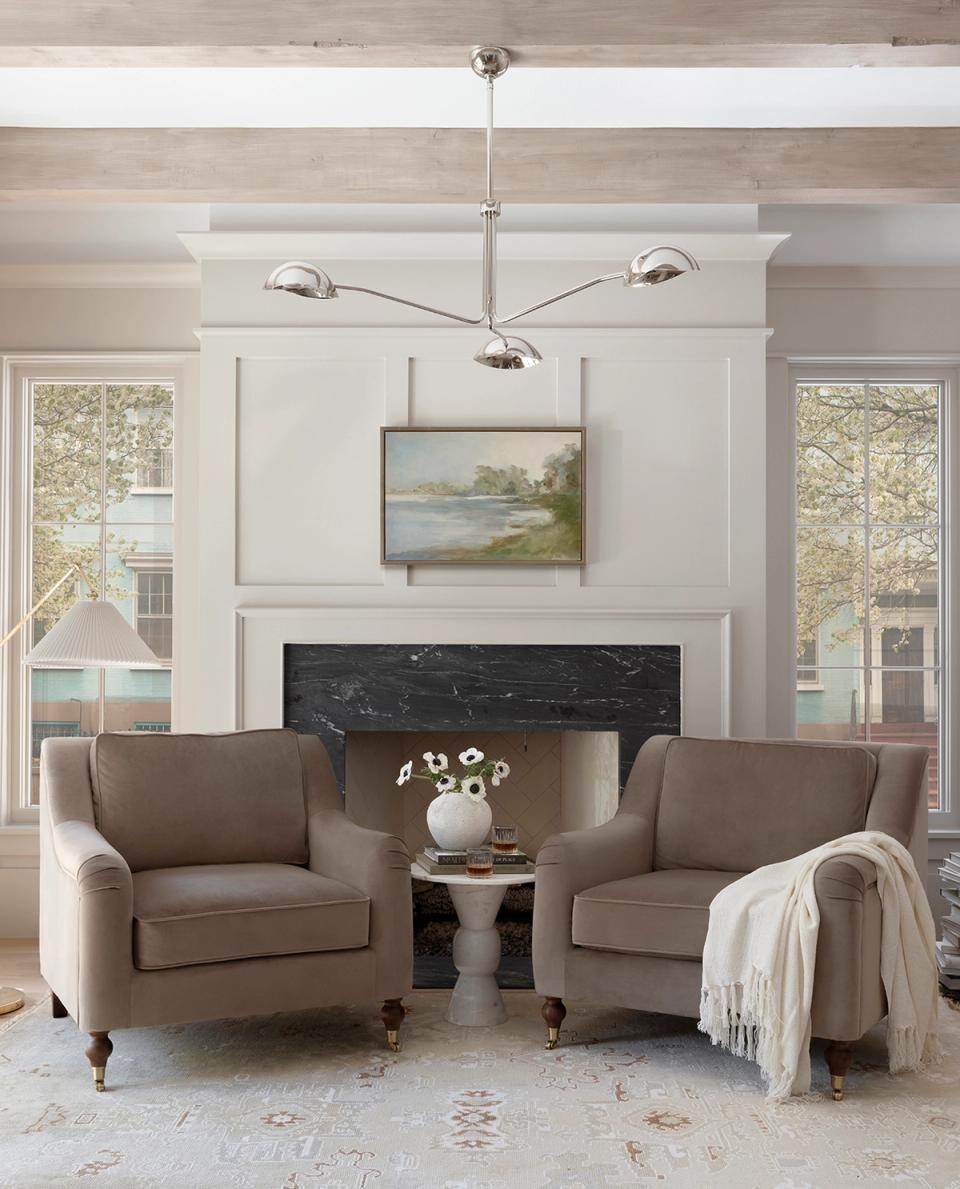 Classic sitting area with taupe chairs, fireplace, soft pendant lighting, and serene minimalist design