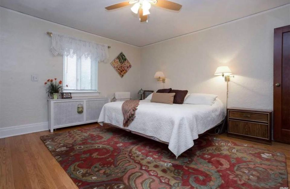 Cozy transitional bedroom blending warm wood tones with red patterned rug and traditional furnishings