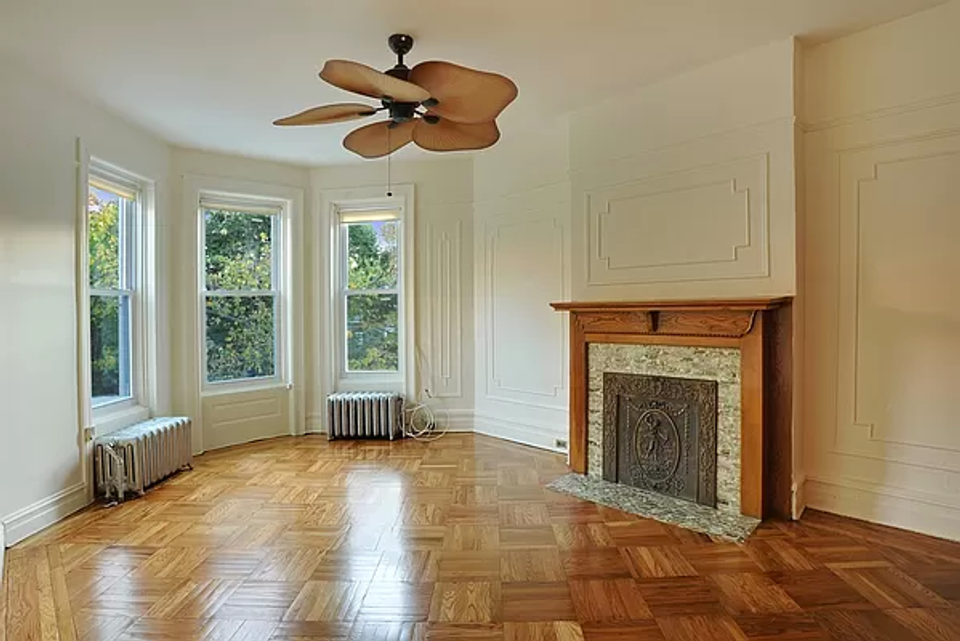 Elegant traditional living space with herringbone wood floors, fireplace, and arched windows