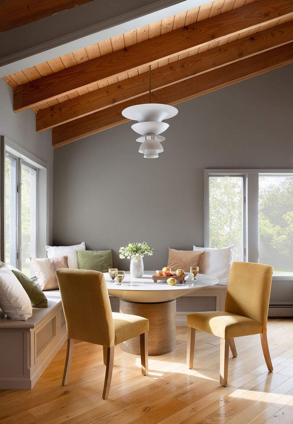 Modern farmhouse dining with mustard velvet chairs, wood table, exposed beams, and warm natural lighting