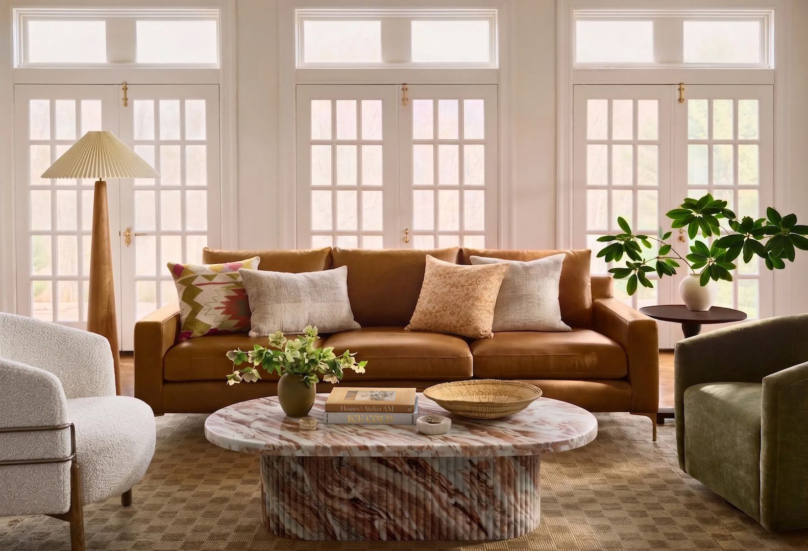 Living room with a camel leather sofa, a green accent chair, and a travertine coffee table