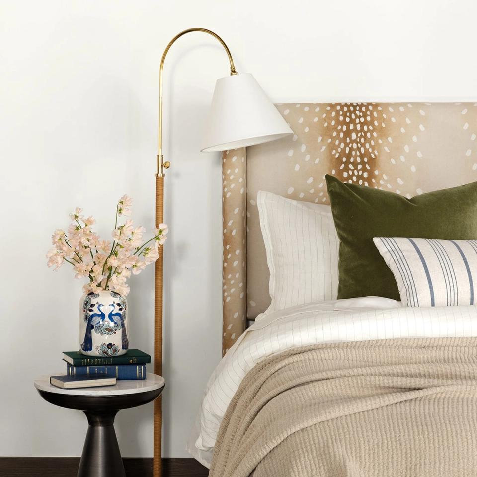 Sophisticated bedroom combining green and white striped pillows with beige textured layers and brass modern lighting