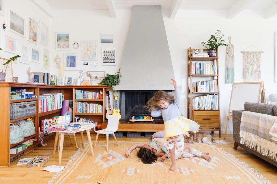 Creative boho family room with warm wood shelving, fireplace focal point, and playful art wall