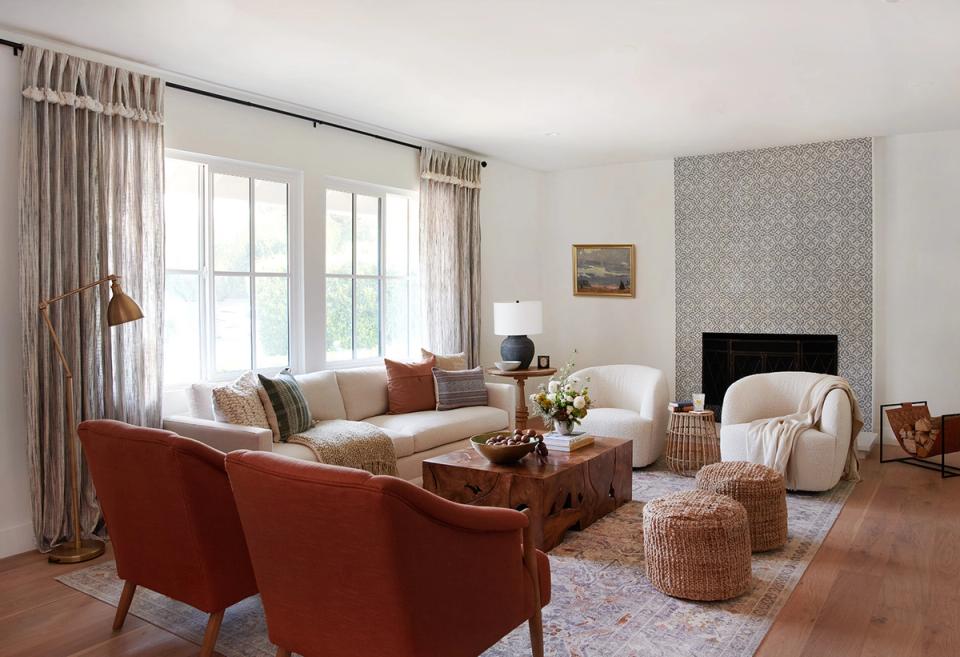 Layered living room blending warm terracotta chair, neutral sofa, patterned wall, and natural wood tones for dimension