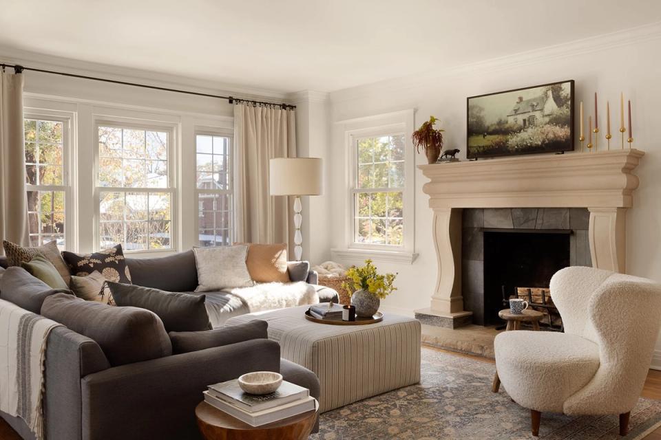 Neutral transitional living room with charcoal sectional, cream accent chair, and light wood fireplace mantel creating a balanced, sophisticated atmosphere