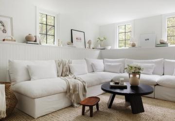 Warm minimalist living room with cream sectional, black round table, and natural wood accents