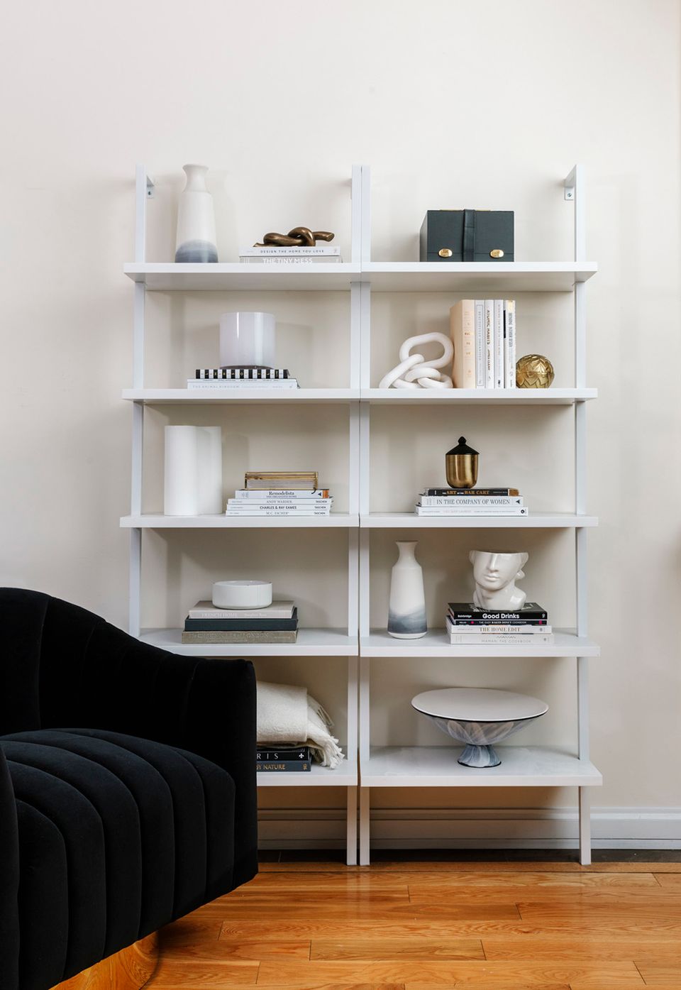 Contemporary white shelving unit with curated minimalist styling, decorative objects, and books arranged in a clean, monochromatic aesthetic