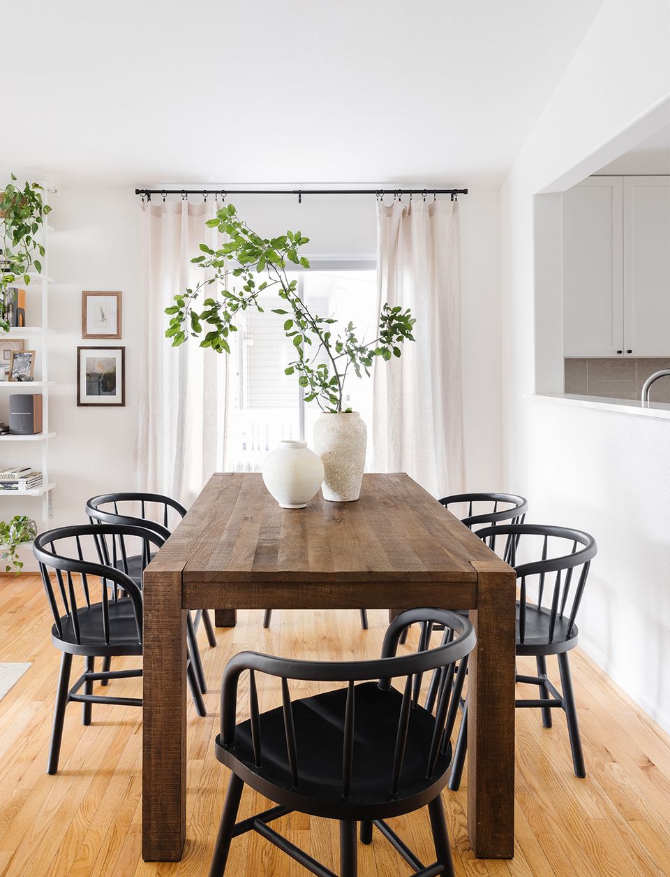 Scandinavian-inspired dining with dark Windsor chairs, wood table, and organic hanging greenery