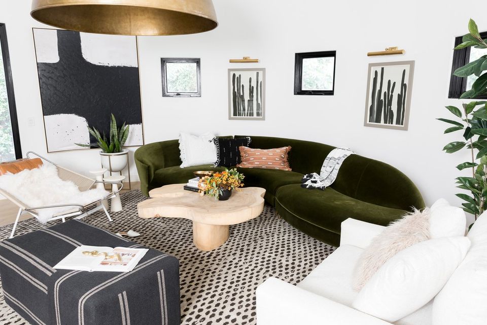 Scandinavian-inspired lounge with curved olive green sofa, natural wood, and botanical greenery accents