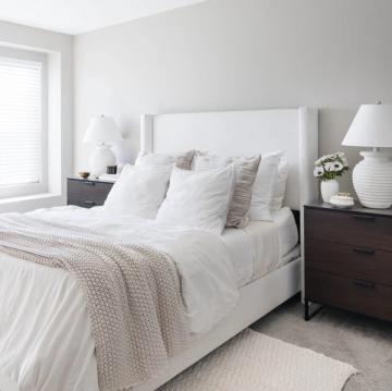 Serene bedroom with white bedding, gray accents, and warm layered neutral tones