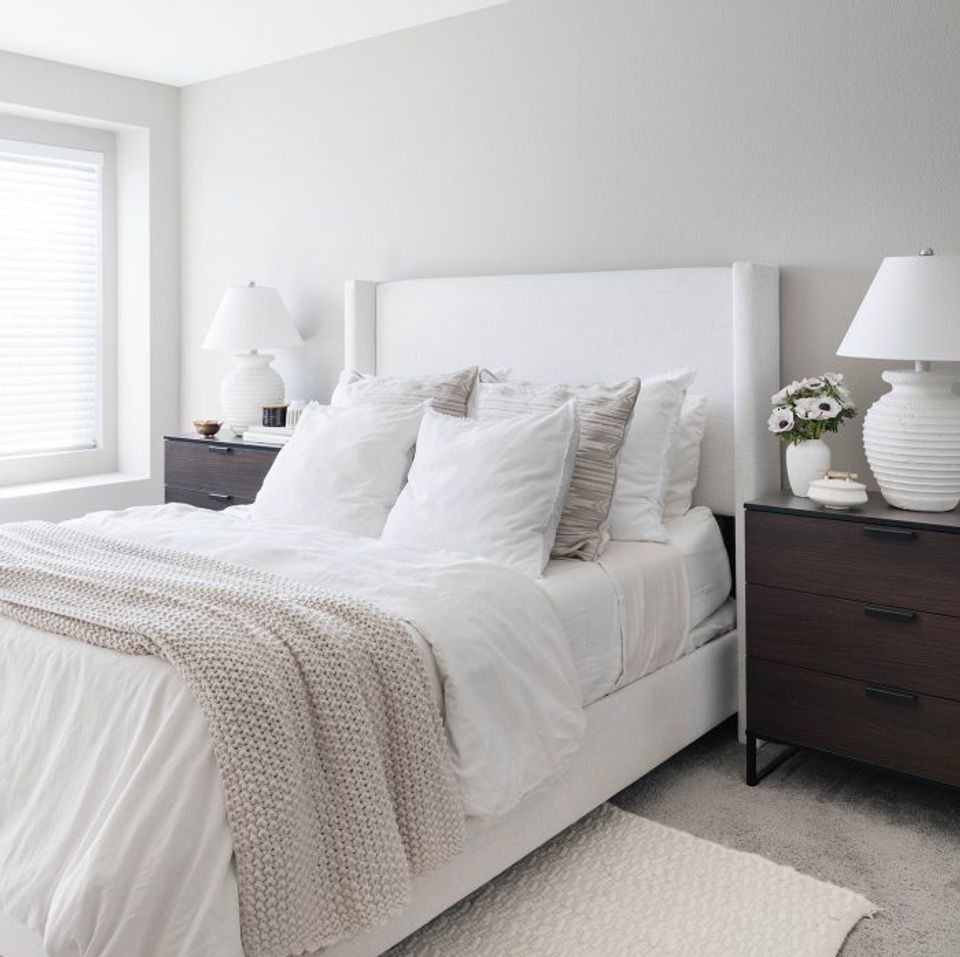 Serene bedroom with white bedding, gray accents, and warm layered neutral tones