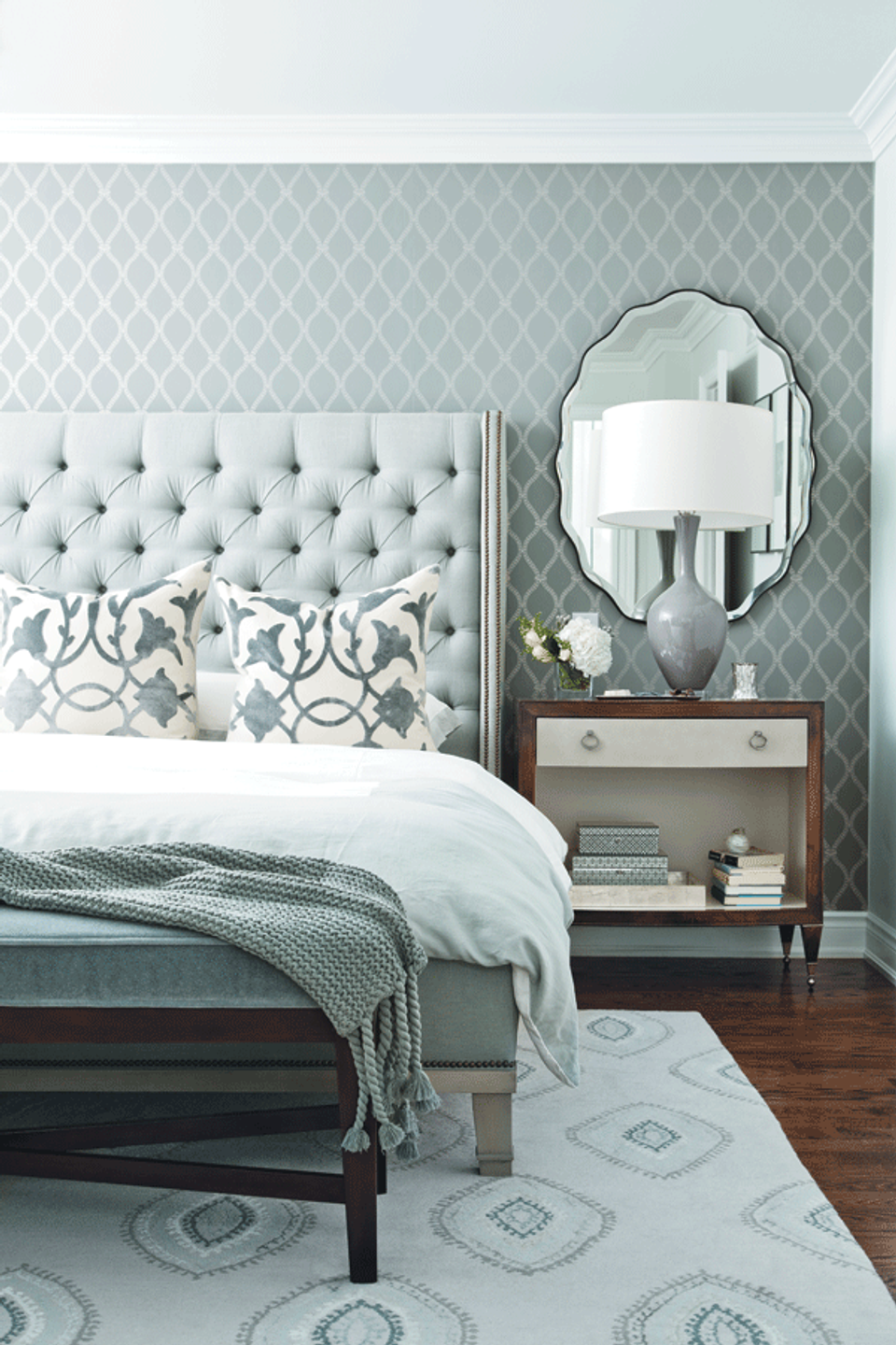 Tranquil bedroom with soft sage quilted wallpaper, tufted headboard, and mid-century nightstand in soothing, cohesive palette.