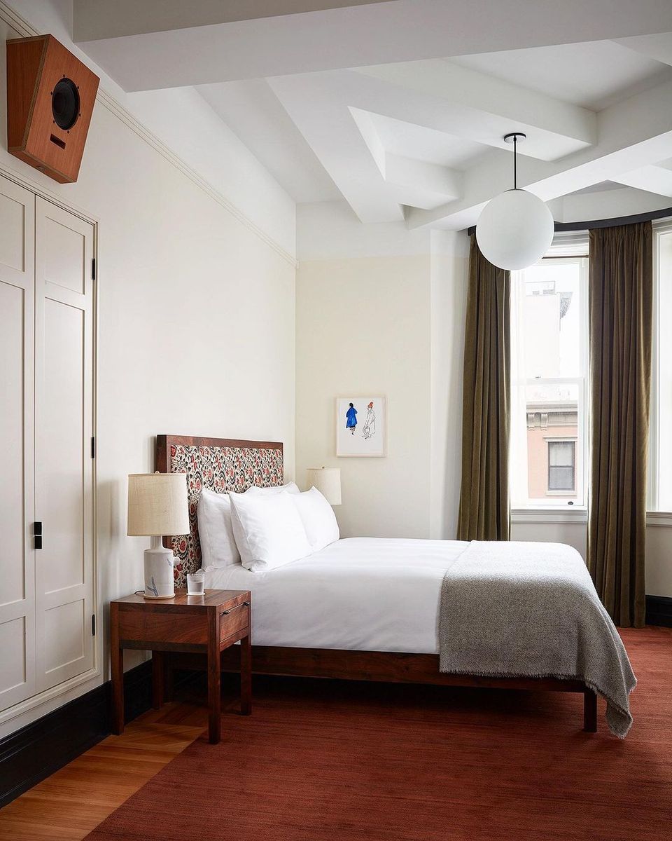 Mid-century modern bedroom with warm wood flooring, cream walls, and rich wood furniture