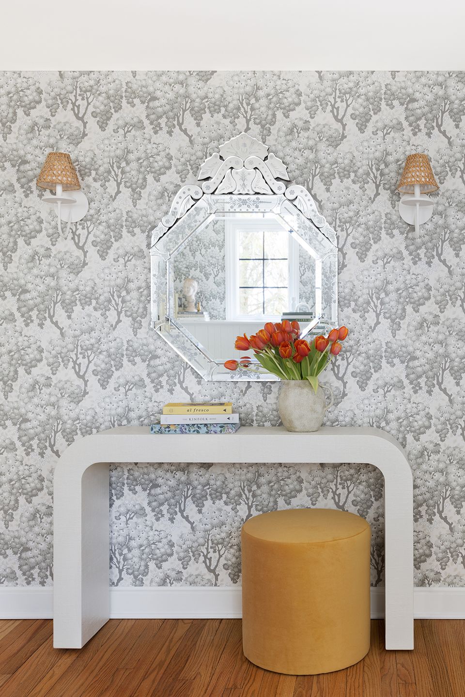 Elegant foyer with botanical wallpaper, white console, octagonal mirror, and fresh tulips