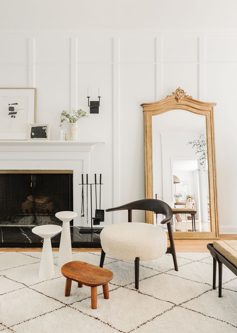 Refined living room blending mid-century modern and traditional styles with cream and black accents, wooden mirror, and minimalist fireplace